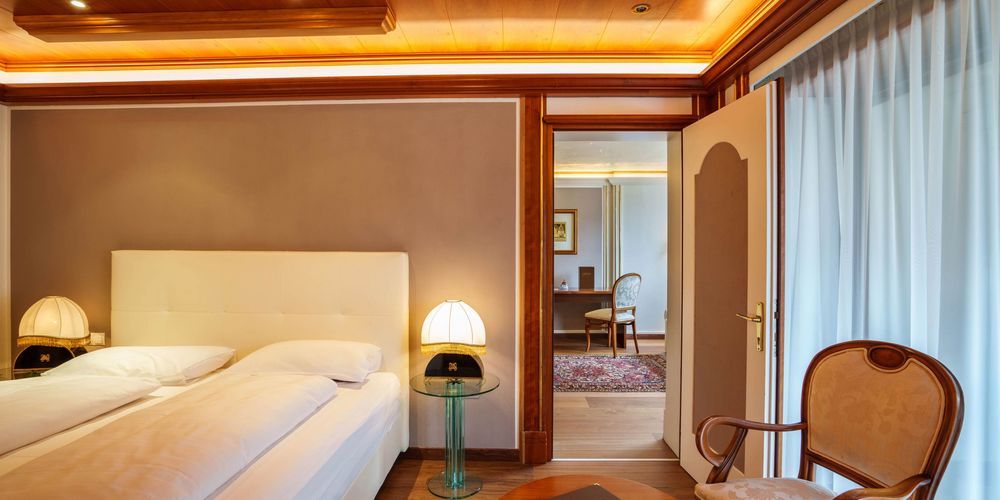 Außenansicht des Hotel Vier Jahreszeiten in Südtirol mit Garten und Pool bei sonnigem Wetter