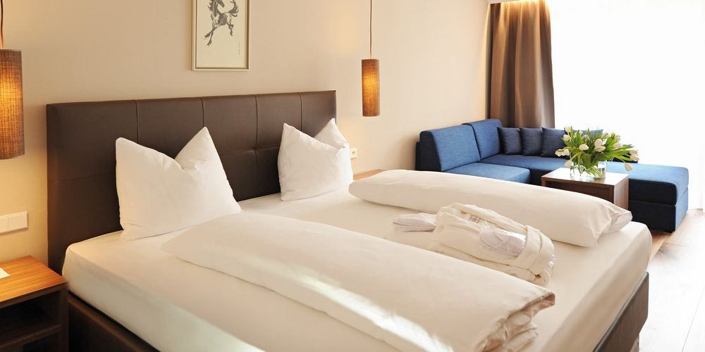 Double room Burgund at Hotel Vier Jahreszeiten with bed, couch and cozy bedroom interior