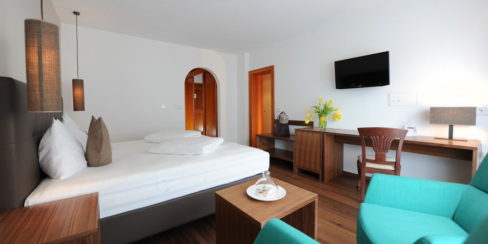 Family room at Vier Jahreszeiten hotel with double bed and cozy sitting area in the Alps