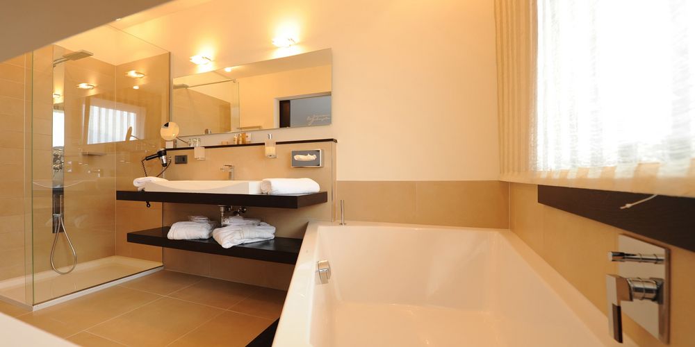 Luxury penthouse designer suite bathroom at Vier Jahreszeiten hotel with modern amenities and elegant burgundy decor