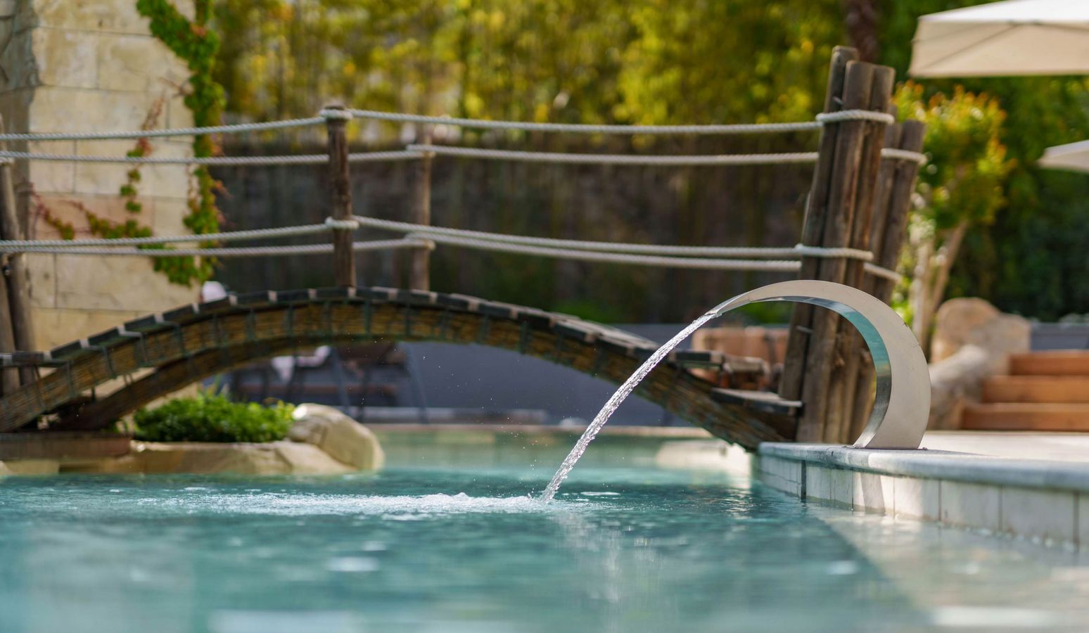 wellnesshotel-Suedtirol-pools-vier-jahreszeiten Außenpool und Wellnessbereich im Vier Jahreszeiten Hotel in Südtirol bei sonnigem Wetter