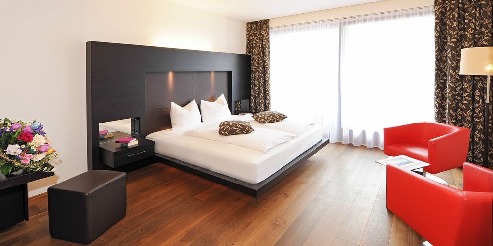 Modern designer penthouse double room with bed and seating area at Vier Jahreszeiten hotel