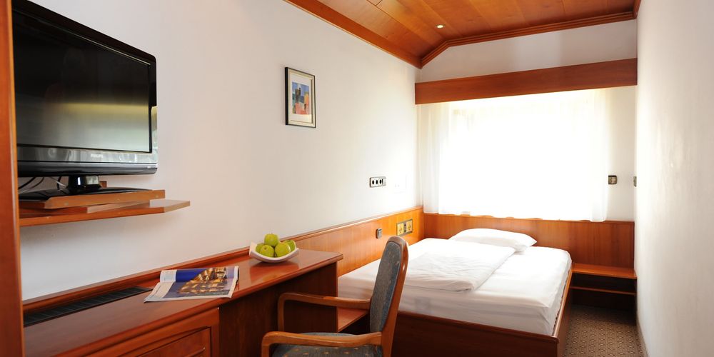 Family room with alpine design at Hotel Vier Jahreszeiten, cozy double bed, wooden furnishings, and mountain view