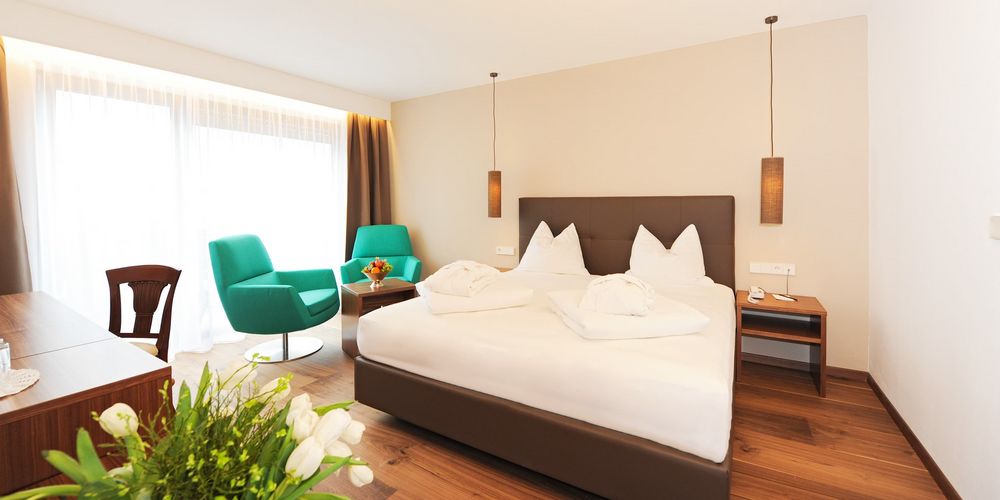 Double room in Vier Jahreszeiten hotel with alpine bed and cozy seating area