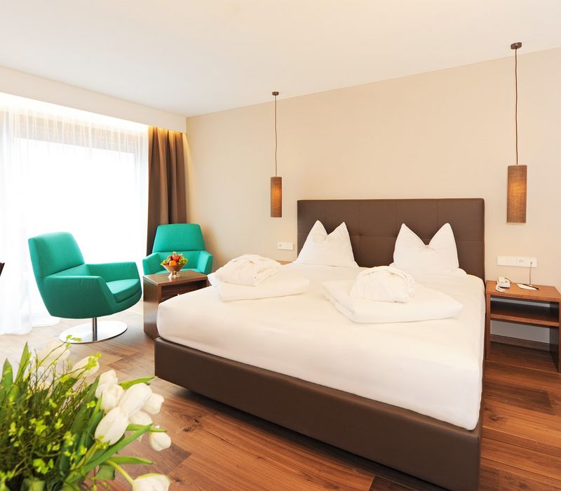 Camera da letto matrimoniale moderna con letto alpino e angolo salotto all’Hotel Vier Jahreszeiten