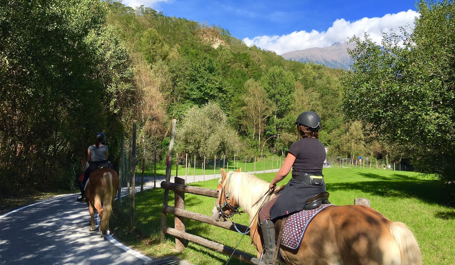 Cavalli e persone che fanno equitazione all’aperto nelle montagne della Val Venosta durante una vacanza presso l’hotel Vier Jahreszeiten