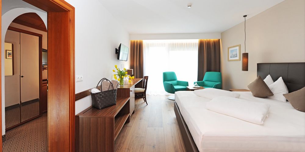 Family room with double bed and sitting area at Hotel Vier Jahreszeiten in South Tyrol